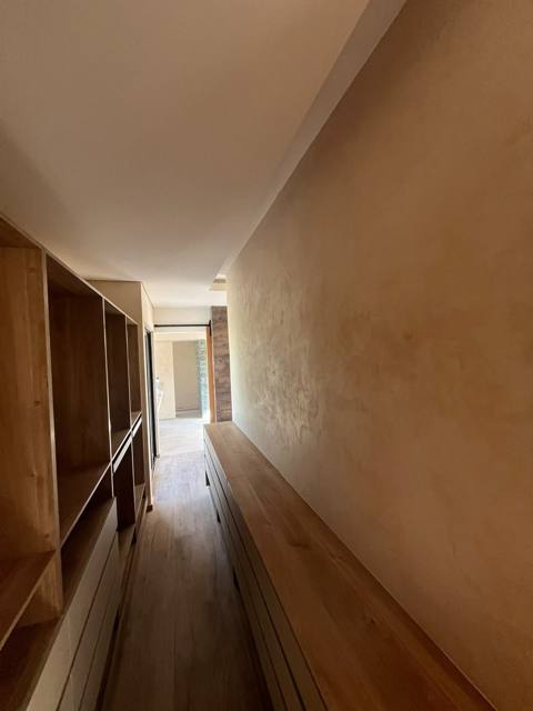Pasillo con muro en chukum y detalles de madera.